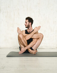 Obraz premium A young man is doing yoga. Yoga coach on a light background.