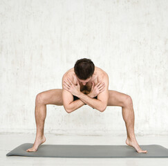 Fototapeta na wymiar A young man is doing yoga. Yoga coach on a light background.