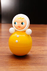 Vertical shot of a plastic doll in white and yellow colors on the wooden table