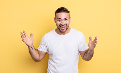young handsome man feeling happy, excited, surprised or shocked, smiling and astonished at...