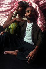 Two Malaysian Indian men in a studio setting with cloth flying in the background, posing against a...