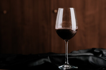 Red wine in a glass on wooden background.