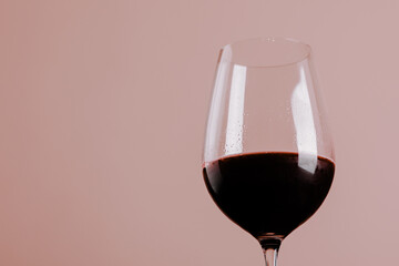 Glass of red wine on pink background.