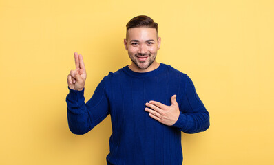 young handsome man looking happy, confident and trustworthy, smiling and showing victory sign, with...