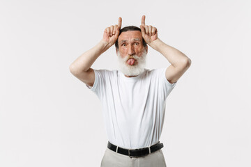 European senior man showing his tongue while making horns gesture