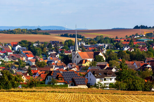 Rural village in autumn with church and solar panel equipped house in center