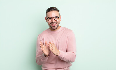 young handsome man feeling happy and successful, smiling and clapping hands, saying congratulations...