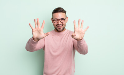 young handsome man smiling and looking friendly, showing number nine or ninth with hand forward,...