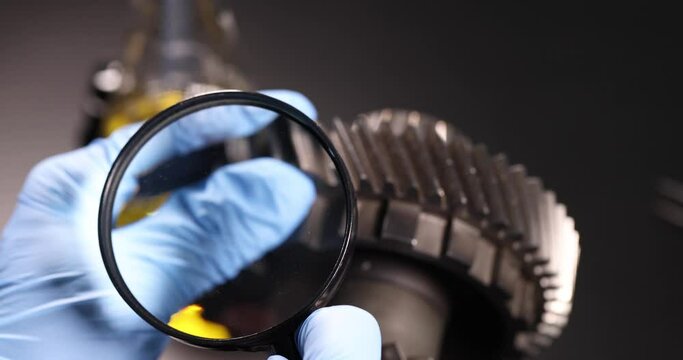 Master repairman looks through a magnifying glass at the differential of the car
