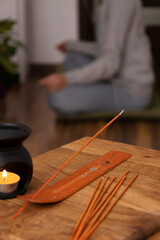 Vertical image.Woman doing her yoga practices on the mat at home.Closeup of smoke of aroma sticks and aroma lamp on the wooden table