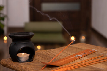Closeup of aroma lamp,candle flame, incense sticks on the wooden desk against yoga mat,candle...