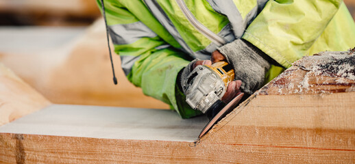 Industrial work carpenter grinds log with electric jointer, construction frame building site of...