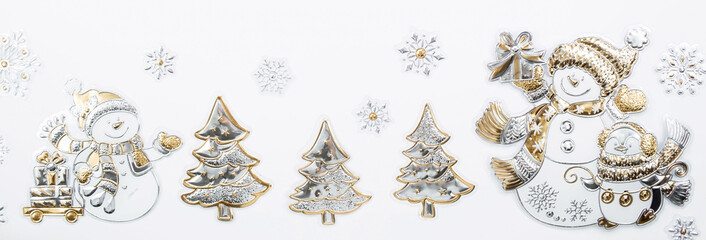 Banner. Happy New Year and Merry Christmas 2022. Snowmen with gifts, spruce and snowflakes made of gold and silver foil on a white background. Flat lay.