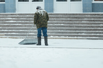 a janitor shovels snow after a blizzard