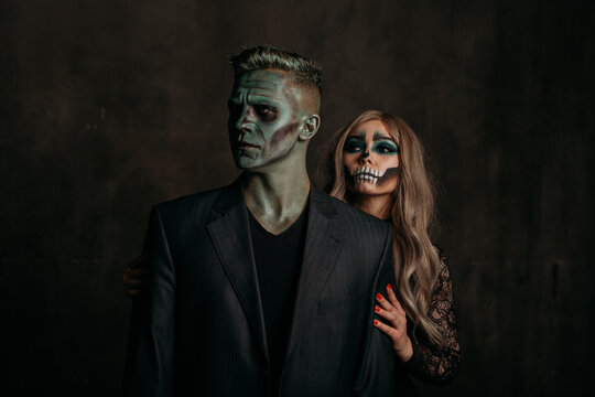 The image of a skeleton girl and the image of a Frankenstein man on Halloween in the dark. an image for a couple on Halloween. the man stands in front, the woman behind and holds him by the shoulders