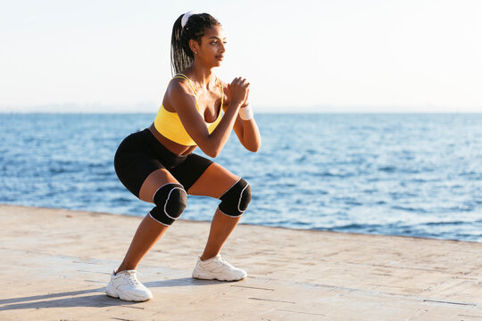 Young female sportsperson doing squats during sunny day