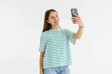 Beautiful young woman is making selfie photo with smartphone on white background