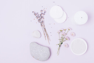 Cosmetic clay near candle with lavender flowers and stones on purple background