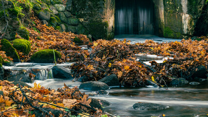 Fototapeta premium Old stone floodgates. Waterfall and blurry water. Autumn view.