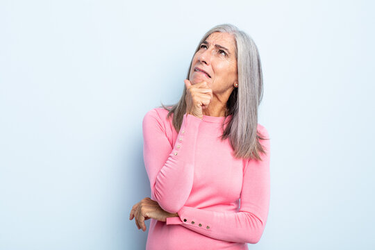 middle age gray hair woman thinking, feeling doubtful and confused, with different options, wondering which decision to make