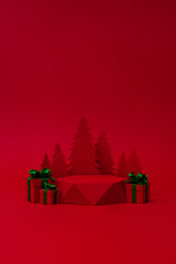 Christmas tree with red pedestal and red gift box with green ribbon on the red background. Christmas creative concept. Paper craft. Place for text.