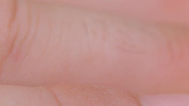 MACRO, DOF: Detailed close up shot of an unrecognizable man's hairy knuckles. Focused macro view of a male's fingers with rugged skin and black hair. Male fingers and knuckles viewed from up close.