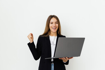 young beautiful business woman having an laptop in hands, leaning on a white wall