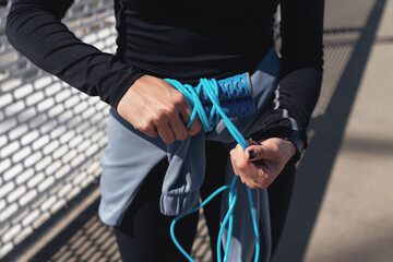 Hands of a young fitness woman holding and bend the skipping or jumping rope after outdoor training...