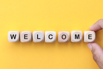 Word welcome on wooden cubes on yellow background
