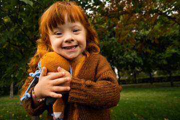 Smiling girl with down syndrome embracing toy in park