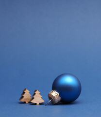 Blue Christmas tree ball with small wooden tree shapes on a blue paper background