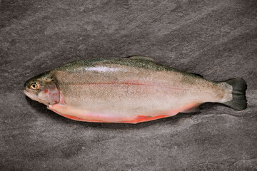 whole rainbow trout on a dark stone table, pink raw fresh fish, salmon, trout recipe,