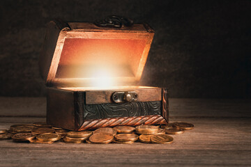 old wooden chest with coins on the table, the chest is open, a bright light from the inside, the...