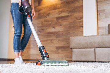 oman cleaning floor and carpet with cordless vacuum cleaner at home. - obrazy, fototapety, plakaty