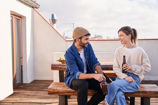 Smiling friends having beer while talking to each other outdoors