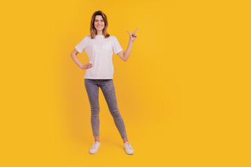 Photo of adviser lady indicate finger empty space wear casual t-shirt jeans on yellow background