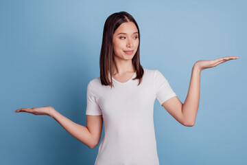 Photo of nice curious smart girl palms weighing invisible objects blank space on blue background