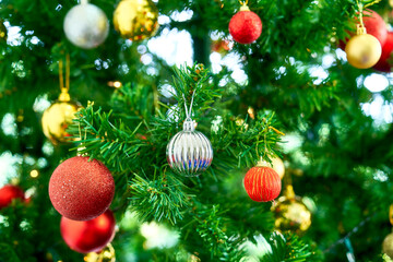 Silver ball decoration hanging on pine christmas tree and light bokeh for celebration event and happy new year