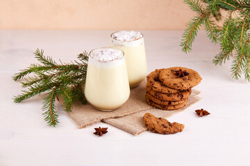 Traditional winter drink eggnog with cookies. It is made from milk with beaten eggs, cinnamon,...