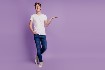 Full body photo of young man happy positive smile hold hand prodcut promo offer advertise isolated on violet color background