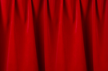 Red silk curtains with smooth waves and dark shadows as rich abstract theatre background.