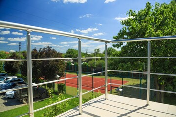 Veranda and metal railing posts on the porch with view on parking and stadium