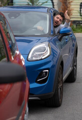 Angry man in the car in the queue yells at the driver in front.