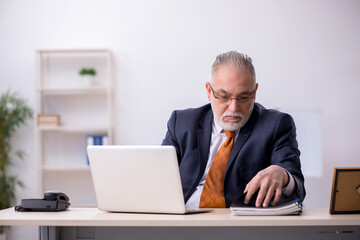 Old male employee working in the office