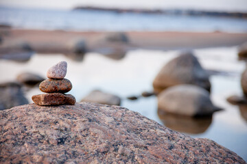 a pyramid of stones on a large stone. rocks on the sea. cold sea