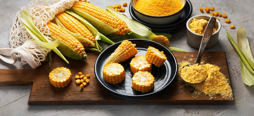 Corncobs and corn groats on gray background.
