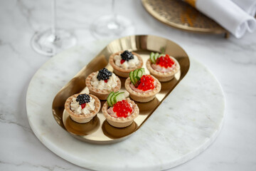 Black and red caviar tartlets on gold plate