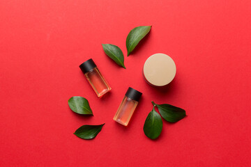 Organic cosmetic products with green leaves on color background. Flat lay