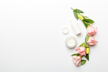 Composition with cosmetic products and beautiful roses on white background. Copy space, flat lay