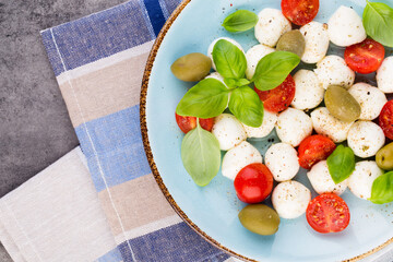 Delicious caprese salad with ripe cherry tomatoes and mini mozzarella cheese balls with fresh basil leaves.